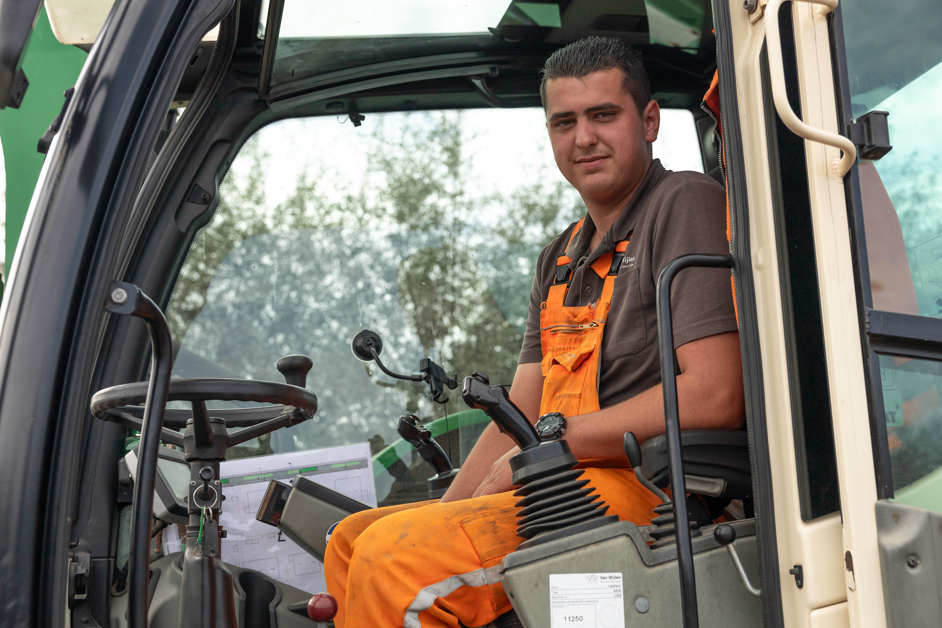 Portret van medewerker Van Wijlen in cabine van werkmachine
